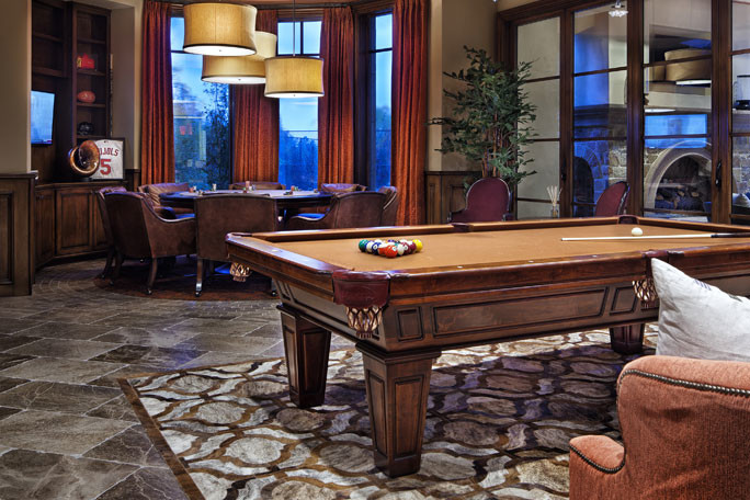 A room with a pool table and chairs