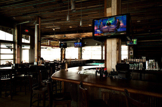 A bar with two chairs and a television on the wall.