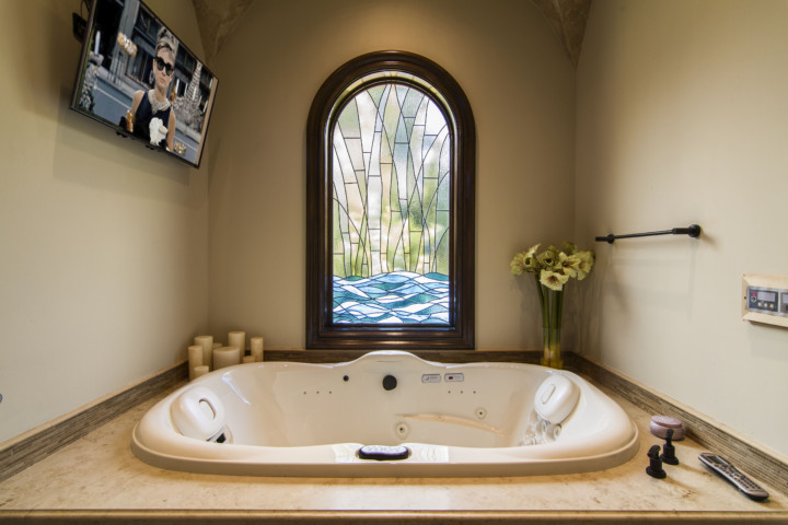A large bathtub in the corner of a bathroom.