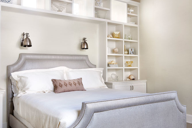A bed with white sheets and pillows in front of two shelves.