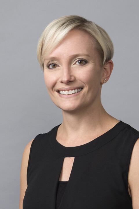 A woman with blonde hair and black top smiling.