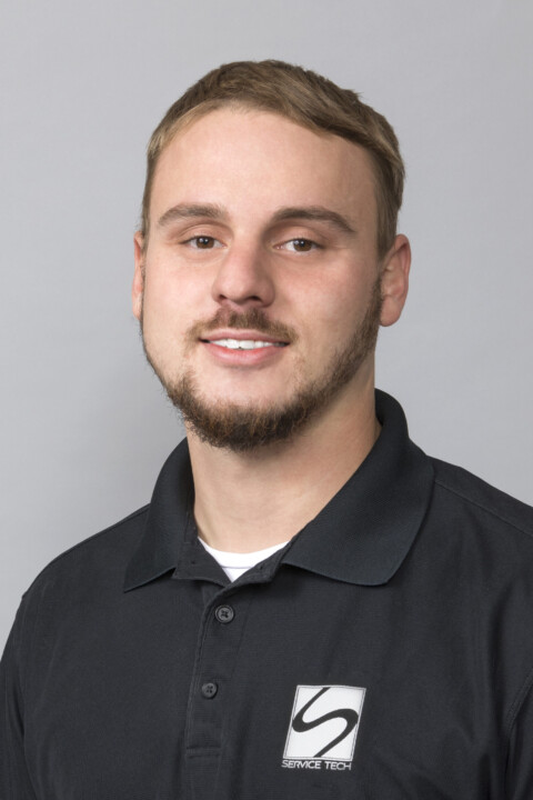 A man in black shirt standing next to wall.