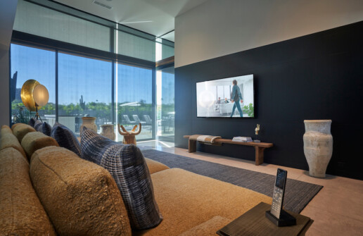 living room with floor-to-ceiling windows with lowered motorized shades, a large screen TV and a Savant remote